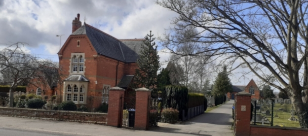 Cemetery lodge, red brick building with stone bands