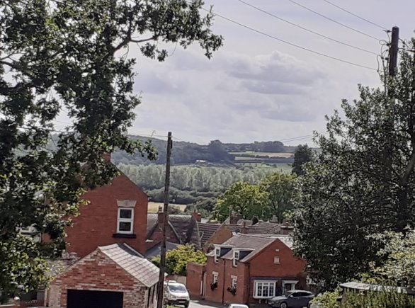 View from near St Andrew's Church looking down Church Bank towards High Street.  View above the rooftops shows the open countryside surrounding Great Easton.