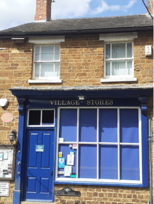 Victorian shop building with blue door adjacent to large shop window with 4 over 4 panes.  Upper floor with two sash windows