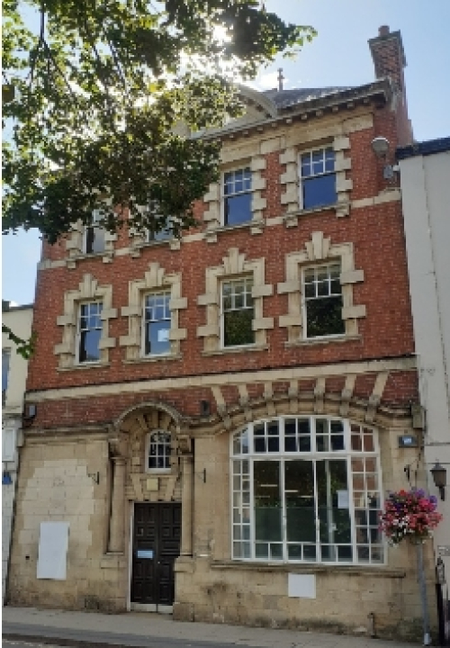 Three storey building with predominantly stone ground floor and brick upper floors with stone dressings to windows
