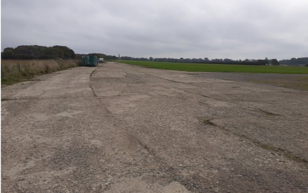 Long concrete road stretching into the distance - former perimeter road of the airfiled